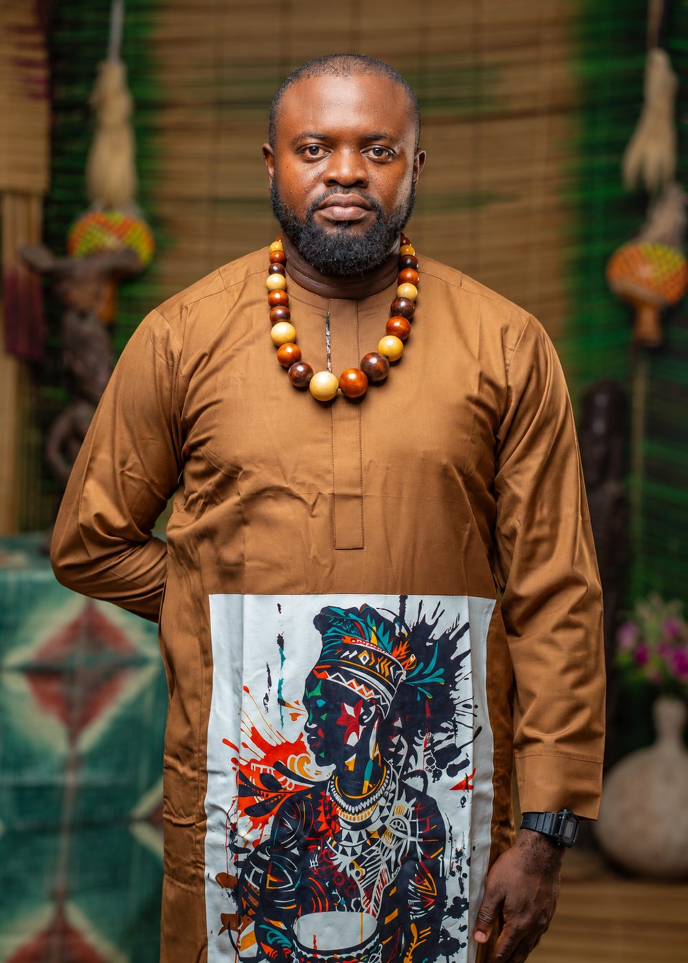Femi Fragile in a brown kaftan and wooden bead necklace